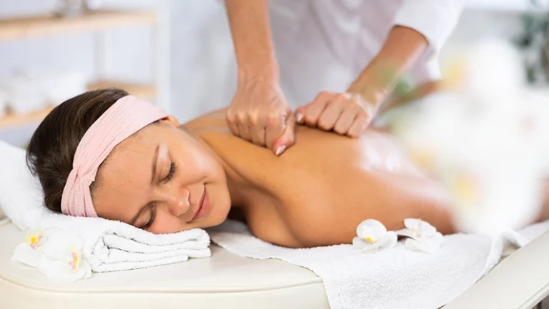 Young woman relaxing on massage table while skilled therapist delivering soothing Swedish back and shoulders massage, promoting stress relief and muscle relaxation