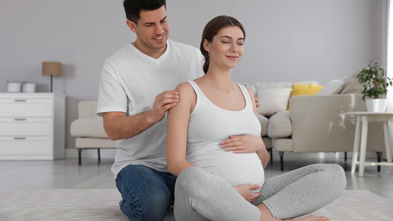 Husband massaging his pregnant wife in living room. Preparation for child birth