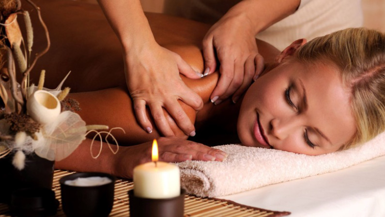 health, beauty, resort and relaxation concept - beautiful woman with closed eyes in spa salon getting massage