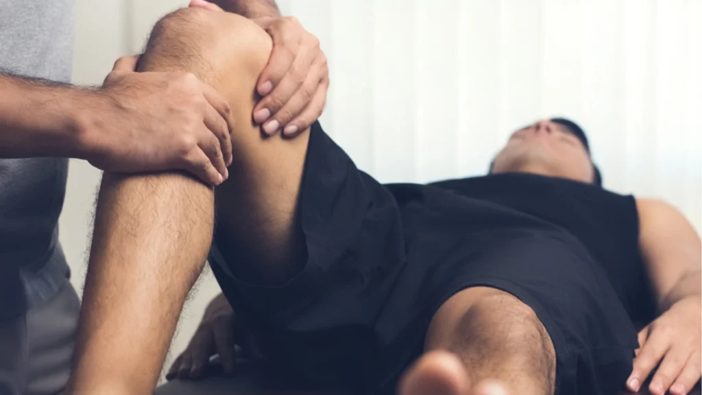 Therapist treating injured knee of athlete male patient - sport physical therapy concept, panoramic web banner