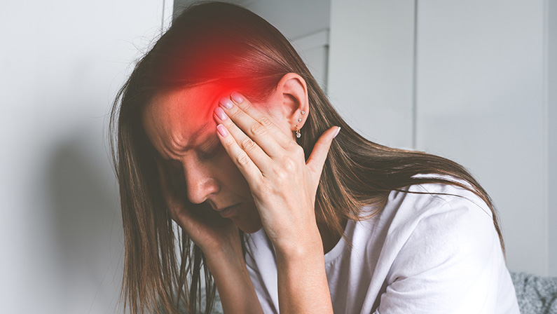 Young woman touching her temples and suffering from head pain, headache or migraine