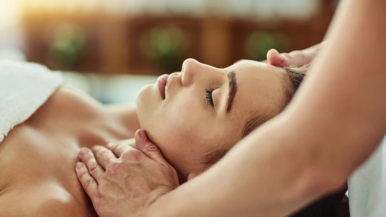 Hands, massage and face of woman for relax, beauty and treatment for client on bed. Towel, spa or lymphatic drainage in salon by masseuse person, facial or stress relief for cosmetic therapy service